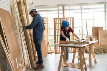 Asian male and woman carpenter working and building furniture together at wood workshop