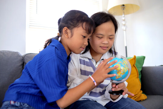 Young Down Syndrome Girl Studying World Map With Her Friend at Home