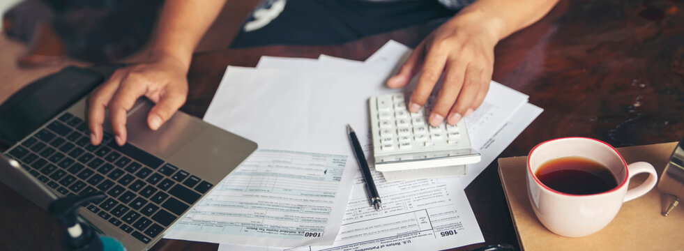 Budget and Tax planning concept. Acountant hand using calculator and review tax form. Represents personal finance, tax preparation, and budgeting, season to pay tax-banner image.