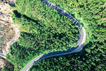Aerial view of a winding road through green forest