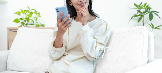 リビングのソファで携帯を持ち微笑む女性