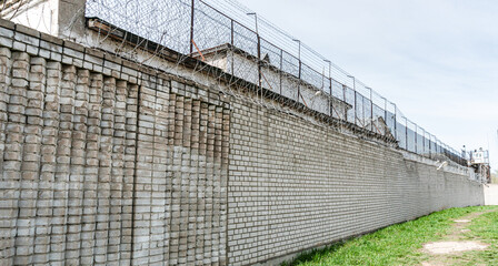 Fototapeta premium Brick Prison Wall with Barbed Wire