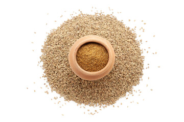 A mud pot filled with organic Carom seeds (Trachyspermum ammi) or Ajwain powder, placed over a heap of whole Carom Seeds, isolated on a white background.