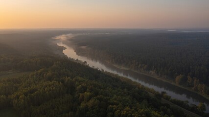 Beautiful soft colors landscape of green forests and lake in the morning with sunrise sky. Nature landscape. Water and forest sustainability concept. Aerial view of a river with green trees.