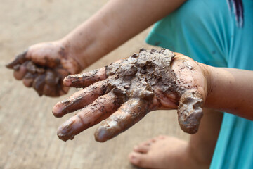 Mud covered hands of a child.  Children playing in mud