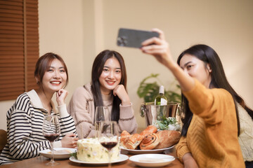 Asian sister friends making selfie and smiling with smartphone. celebrating with Birthday cake.