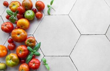 Freshly harvested tomatoes and basil scattered on a hexagonal tile kitchen surface during summer