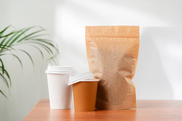 Three beverage containers and a paper bag on a wooden table