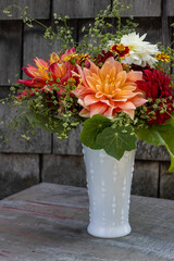 A vibrant bouquet with orange, red, and white flowers in a white vase