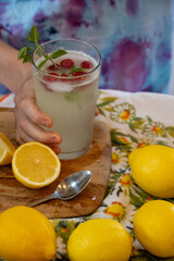 Hand holding a refreshing lemonade with raspberries and mint garnish