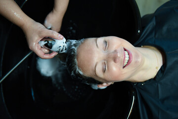 Client smiling while enjoying a foamy hair wash at the salon si