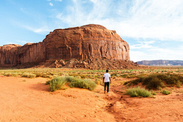 Man walking alone toward massive sandstone in Monument Valley