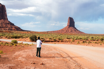 Man gazes at Monument Valley's iconic buttes under cloudy skies