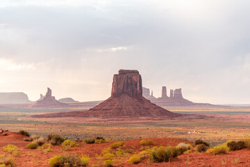Monument Valley's buttes under a soft, cloudy sky with desert