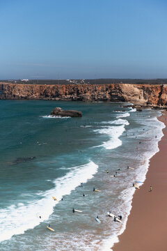 Surfers on the waves at Praia do Tonel in Sagres, Algarve, Portugal.
