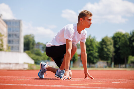 Young male athlete in starting position on running track