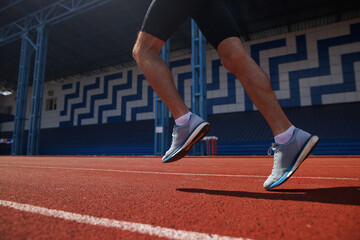 Runner's legs in motion on red track at outdoor stadium