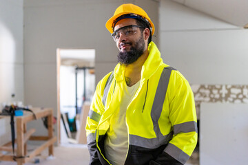 A cheerful construction worker in a safety vest and helmet beams with pride during house remodeling, demonstrating professionalism and skill while ensuring quality and safety in urban renovation