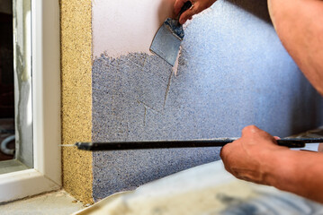 Applying decorative mosaic plaster on the wall.