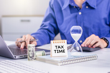 TAX TIME CONCEPT. A man at a desk works on taxes. A notepad reading 