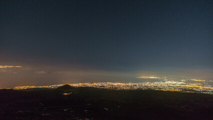 Illuminated city of Catania from Etna at starry night with volcanic landscape during winter time, Catania, Sicily, Italy