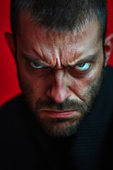 Obraz premium Angry and Expressive Man Located Against Red Background, exhibiting a strong of intense anger