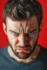 Obraz premium Angry and Expressive Man Located Against Red Background, exhibiting a strong of intense anger