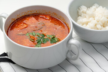 Bowl of curry with pieces of meat and a side of steamed rice arranged neatly for a meal