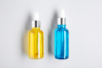 Essential oils in bottles on light background, top view