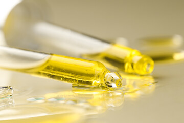 Cosmetic oil and pipettes on dark beige background, closeup