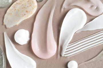 Smears of different cosmetic products on grey background, flat lay