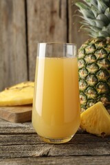 Tasty pineapple juice in glass and fresh fruit on wooden table, closeup