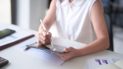 Asian businesswomen reading marketing business report on digital tablet and finance document of new business to taking notes while analyze investment and market stock of new startup in outside office