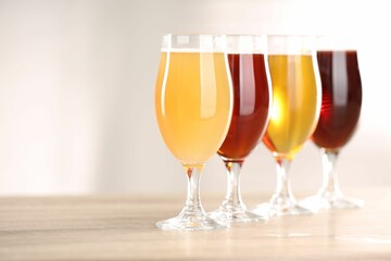 Glasses with different types of beer on wooden table indoors, closeup. Space for text