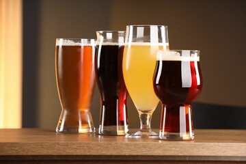 Glasses with different types of beer on wooden table indoors