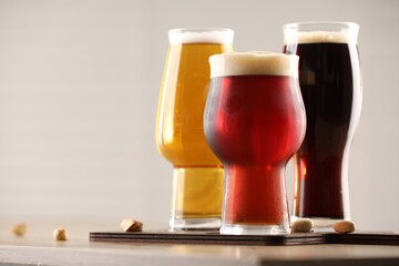 Glasses with different types of beer on wooden table indoors, closeup. Space for text