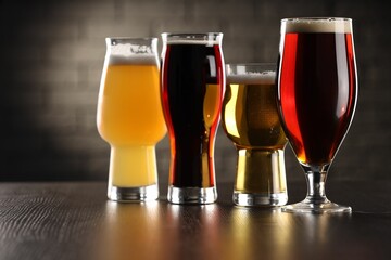 Glasses with different types of beer on wooden table in bar