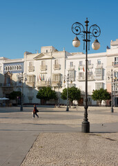 Cádiz city square, with its buildings and lampposts, at sunset.