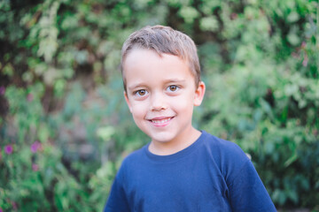 People, childhood, school age and lifestyle concept. Image of a handsome, adorable Spanish schoolboy, dressed in a dark blue t-shirt, looking at the camera with a wide, happy smile.