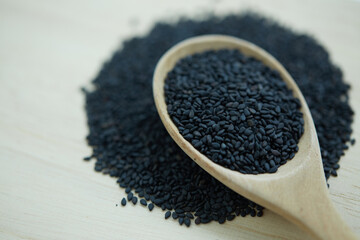 Black sesame seeds in wooden spoon on wooden background, Selective focus of black sesame