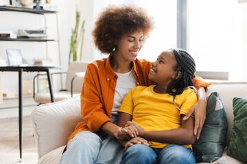 Smiling mother hugging her attractive kid daughter tenderly