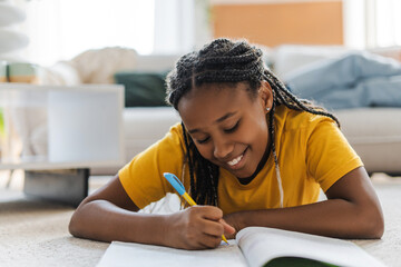 Concentrated happy girl, teenager drawing in sketchbook at home
