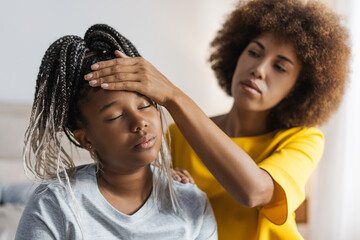 Mother touching forehead checking temperature unhealthy small daughter at home