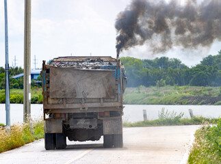 A loaded truck ride on the road with thick black smoke from the exhaust