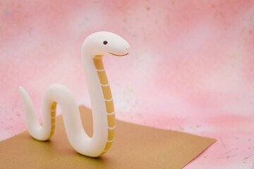 ピンク柄の背景に蛇の立体人形　巳年　年賀素材　