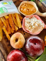 Evening snack french fries, apple, peaches and juice in a wooden try.