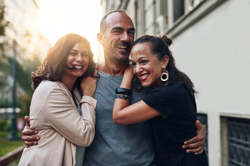 Happy people, friends and city with hug for commute, travel or day out together in an urban town. Young, group and enjoying social, laughing or fun time for bonding, support or trust on sidewalk