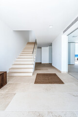 Modern minimalist entryway with a staircase leading to a bright open space near the ocean on a sunny day