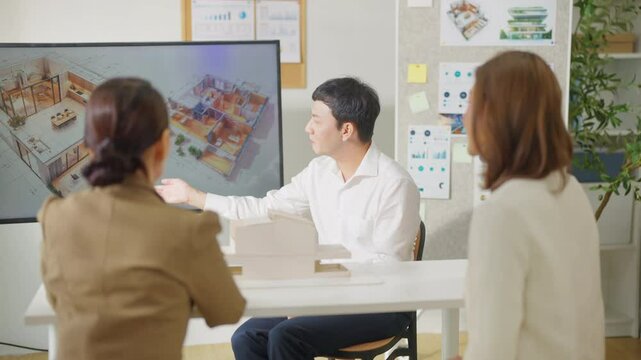Asian Architects and department manager teamwork meeting discussion and presentation 3D architectural displayed model of energy efficient and sustainability home design in office conference room.