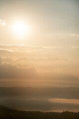 Majestic Mountain Landscape Covered in Mist with Sun Rays Breaking Through Clouds